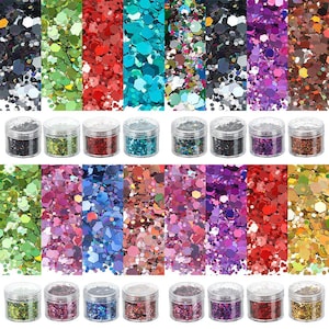 May include: A collection of sixteen clear plastic jars filled with assorted colours of hexagonal craft glitter. The set includes various shades of green, red, blue, purple, black, and gold, with each jar containing a mix of different sized flakes.