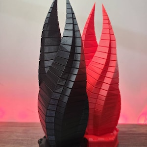 May include: Two 3D printed sculptures of the iconic Portal 2 companion cubes. One is black and the other is red.