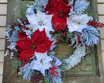 May include: A Christmas wreath with red and white poinsettias, frosted pine branches, and red berries.