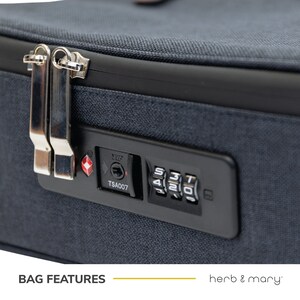 Może przedstawiać: Granatowa torba podr&oacute;żna z zatwierdzoną przez TSA kombinacją zamka. Zamek ma czerwony diament i napis "TSA007".