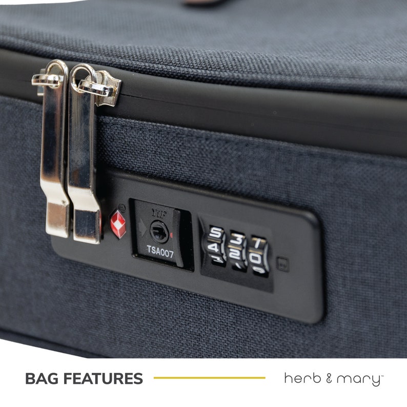 Może przedstawiać: Granatowa torba podr&oacute;żna z zatwierdzoną przez TSA kombinacją zamka. Zamek ma czerwony diament i napis "TSA007".