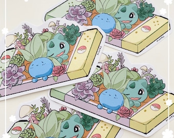 Könnte beinhalten: Drei Aufkleber mit einem grünen und blauen Pokémon-Charakter auf gelbem Hintergrund. Das Pokémon ist von grünen Pflanzen und Blumen umgeben. Die Aufkleber tragen den Text "MIDORI".
