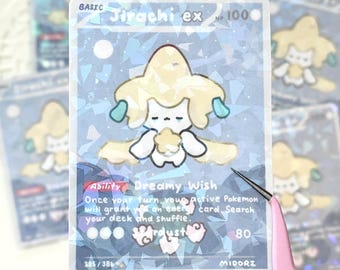 May include: A holographic trading card featuring a cartoon character with a yellow head and white body. The card reads "Jirachi ex" and "Dreamy Wish". The card has a blue and white background with the number 80.