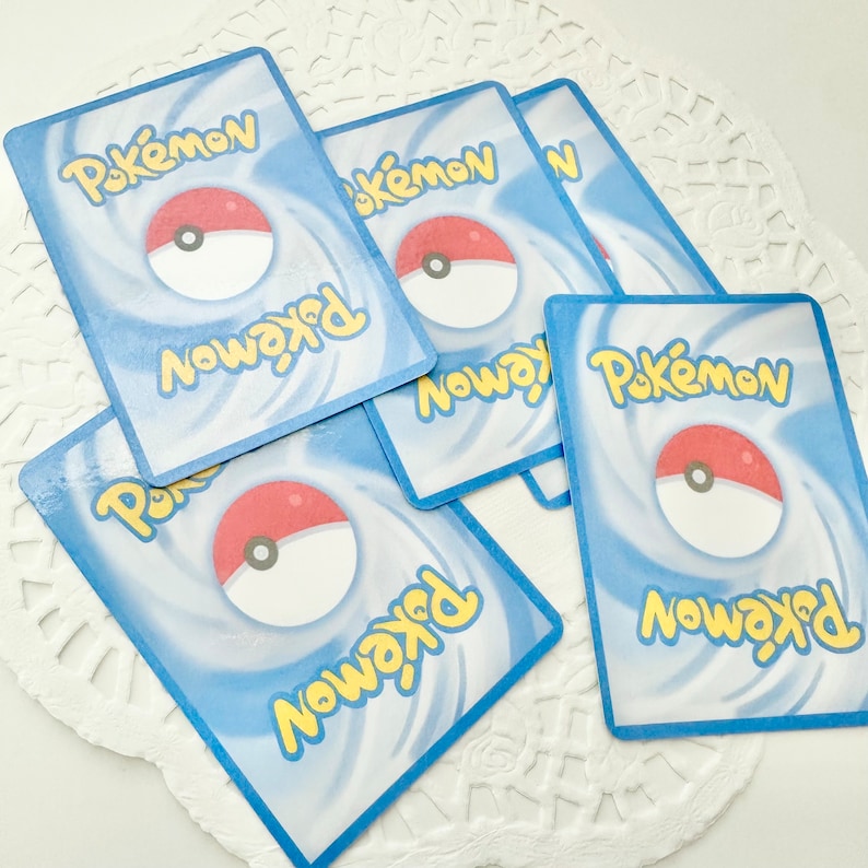 May include: Five blue and yellow Pokemon trading cards with a white background and a red and white Pokeball graphic. The cards have the text "Pokemon" and "Pokemon Now" on them.