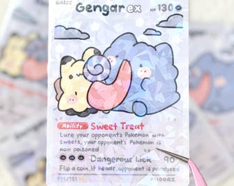 May include: A holographic trading card featuring a cartoon Gengar ex and a yellow creature. The card has the text "Gengar ex HP 130" and "Sweet Treat" and "Dangerous Lick" abilities. The card is 099/151.
