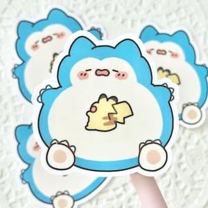 May include: A collection of stickers featuring a blue and white cartoon character with a yellow graphic. The character has a sleepy expression and is holding a yellow creature. The stickers have a white border and are on a white background.