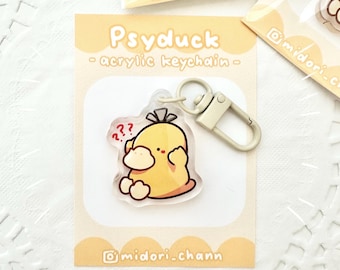 May include: A yellow Psyduck Pokemon character keychain made of acrylic. The keychain features a small, white question mark above the character's head. The keychain is attached to a silver metal ring and clasp.