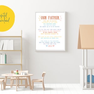May include: A printable wall art design featuring the Lord's Prayer, "Our Father", in a colorful, handwritten font. The text is framed in a white frame and set against a white wall.