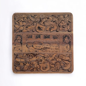 May include: A wooden plaque with a dark brown stain and intricate engravings. The plaque features a skull, a skeleton, and the words "Vado Mori", "Sequevere Me", and "Mori".