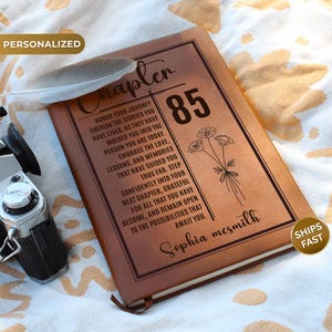 May include: A brown leather-look journal featuring the text Chapter 85, a floral line drawing, and the name Sophia McSmith. The cover includes an inspirational quote about honoring one's journey, memories, and future possibilities.