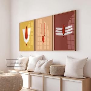 May include: Three framed prints with minimalist geometric designs in red, white, and yellow. The prints are hung on a white wall above a wooden bench with white cushions.