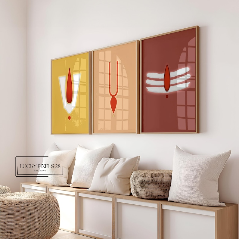 May include: Three framed prints with minimalist geometric designs in red, white, and yellow. The prints are hung on a white wall above a wooden bench with white cushions.