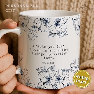May include: A white ceramic mug featuring a dark blue floral line art pattern. The center displays the text: A quote you love, styled in a charming vintage typewriter font. -AUTHOR. The mug has a curved handle and a smooth, glossy finish.