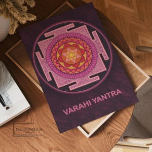 May include: A pink and orange mandala with a geometric design, surrounded by a black square frame. The text "VARAHI YANTRA" is written in a dark pink font at the bottom of the image.