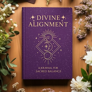May include: A purple journal with the words "DIVINE ALIGNMENT" in gold lettering. The cover features a celestial design with a sun, moon, and stars. The text "A JOURNAL FOR SACRED BALANCE" is below the design. The journal is surrounded by flowers.