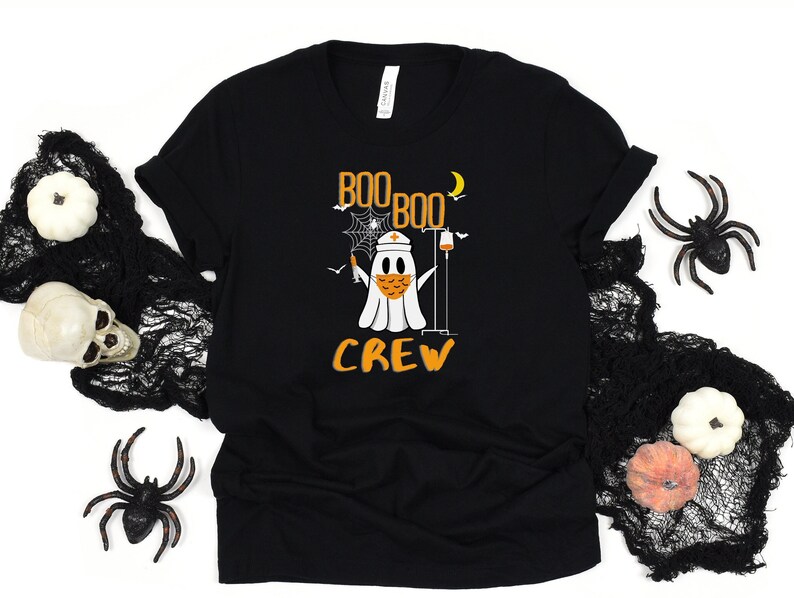 May include: Black t-shirt with a white ghost wearing a face mask and holding a syringe. The text "Boo Boo Crew" is printed on the shirt.