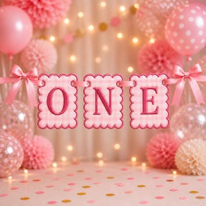 May include: A pink banner with the word "ONE" in a gingham pattern is strung between pink bows. The background features pink balloons, paper decorations, and confetti, creating a festive atmosphere. Soft lighting and a light pink backdrop complete the celebratory scene.