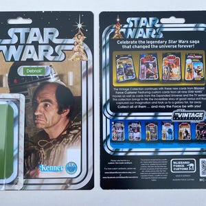 Peut inclure: Une carte Star Wars vintage représentant un personnage de l'univers Star Wars. La carte est verte et blanche avec le texte "Debnoli" et "Kenner" dessus. Le dos de la carte présente une collection de cartes Star Wars de la collection Vintage.