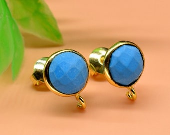 May include: A pair of gold stud earrings with light blue faceted gemstone accents. The earrings have a small loop on the bottom.