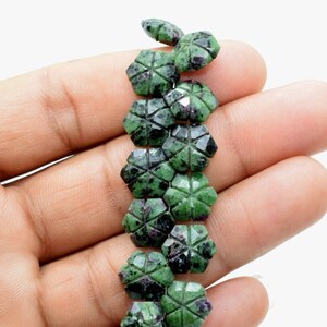 May include: A strand of green and black gemstone beads, each bead is carved into a starburst shape.