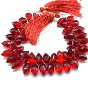 May include: A strand of red faceted crystal beads, with a tassel at each end. The beads are shaped like teardrops and are strung on a clear thread.