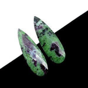Op de afbeelding: Twee traanvormige groene en paarse edelstenen met een gemarmerd patroon.