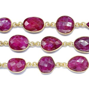 以下が含まれることがあります： ファセットカットのルビーの宝石がついたゴールドチェーンネックレス。ネックレスは、楕円形と涙滴型の石の繰り返しパターンを特徴としています。