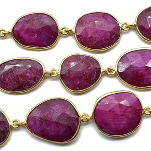 以下が含まれることがあります： ゴールドのアクセントが付いたルビーのビーズのストランド。ビーズは楕円形で、ファセット加工が施されています。