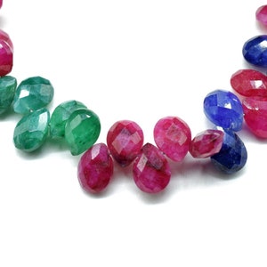 May include: A strand of faceted gemstone beads in shades of red, green, and blue. The beads are oval-shaped and have a polished finish.