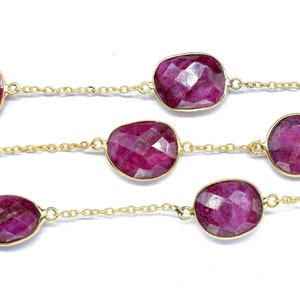 以下が含まれることがあります： 複数の楕円形のルビーの宝石が付いたゴールドチェーンネックレス。チェーンは小さな連結されたゴールドサークルで作られています。