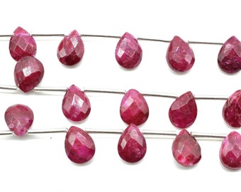 May include: A strand of faceted ruby gemstone beads in a teardrop shape. The beads are strung on a silver wire.