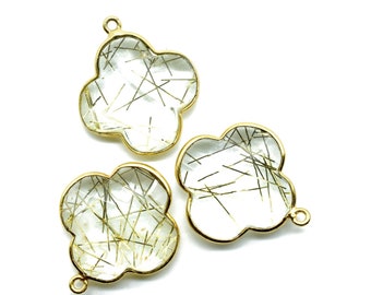 Puede incluir: Tres abalorios de metal dorado con un diseño de trébol de cuatro hojas. Cada abalorio presenta una piedra de cuarzo transparente con inclusiones doradas.