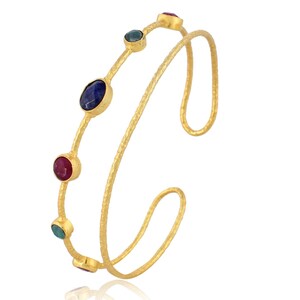 May include: A gold bangle bracelet with a double band design. The bracelet is adorned with five gemstones in shades of blue, green, and red.