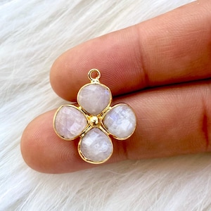Peut inclure: Un pendentif en or avec un design trèfle à quatre feuilles et des pierres précieuses en pierre de lune blanche.