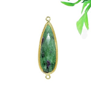 May include: A gold-toned pendant with a green and purple gemstone in a teardrop shape.