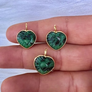 May include: Three gold-plated heart-shaped pendants with green jade inlays. The pendants feature a detailed carved design.