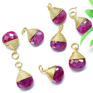 May include: Eight gold-wrapped ruby gemstone pendants with a faceted finish. Each pendant has a loop for attaching to jewellery.