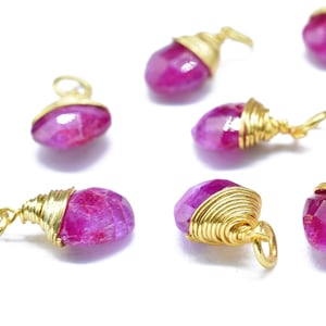 Puede incluir: Una colección de siete colgantes de piedra rosa envueltos en alambre dorado. Cada colgante tiene una forma y un tamaño únicos.