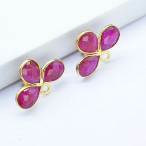 May include: Two gold-tone charms with three pink gemstone accents each. The charms have a loop for attaching to jewelry.