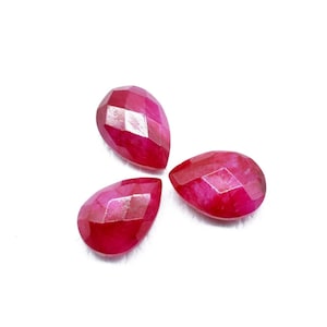 Op de afbeelding: Drie facetgeslepen edelstenen in druppelvorm in een diepe roze kleur.