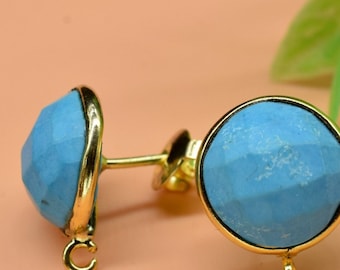 May include: A pair of gold earrings with blue gemstone accents. The earrings have a round shape and a textured surface.