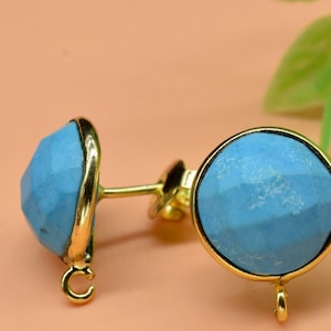May include: A pair of gold earrings with blue gemstone accents. The earrings have a round shape and a textured surface.