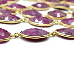 Puede incluir: Un collar largo hecho de piedras preciosas rosadas facetadas de forma ovalada con detalles en metal dorado.