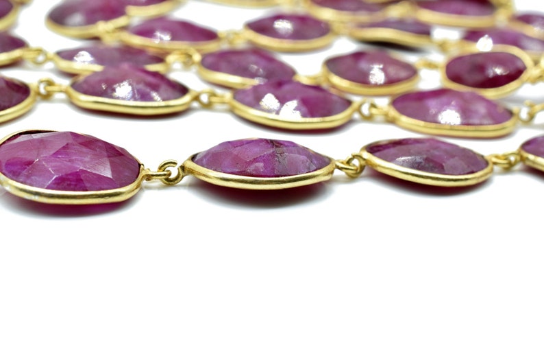 Puede incluir: Un collar largo hecho de piedras preciosas rosadas facetadas de forma ovalada con detalles en metal dorado.