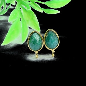 Puede incluir: Un par de pendientes de oro con gotas de piedras preciosas verdes. Los pendientes tienen forma de lágrima y un diseño sencillo.