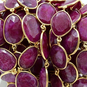 Puede incluir: Una hebra de cuentas de piedras preciosas de color rojo rub&iacute; con detalles dorados. Las cuentas son de forma ovalada y tienen un acabado facetado. Las cuentas est&aacute;n enhebradas en una cadena dorada.