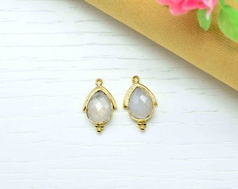 May include: Two gold-tone pendant charms with a pear-shaped moonstone gemstone. Each charm has a decorative, arched design and a small, round bead at the bottom.