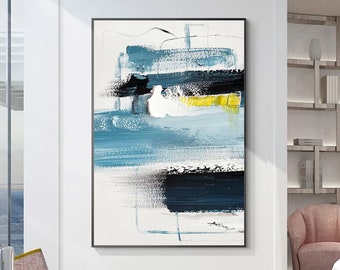 May include: Abstract painting with blue, black, white, and yellow brushstrokes. The painting is framed in a black frame.