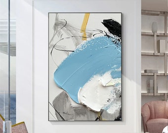 May include: Abstract art painting in a black frame. The artwork features thick brushstrokes of light blue, white, black, and yellow paint on a textured white background. Grey and black lines add detail to the piece.