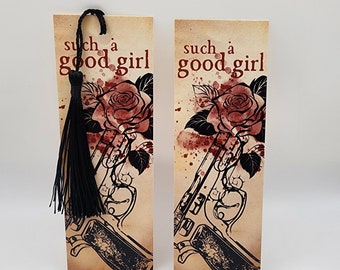 May include: Two bookmarks with a vintage aesthetic featuring a black and white illustration of a rose and a gun with red watercolor splatters. The text "such a good girl" is printed in red on each bookmark.